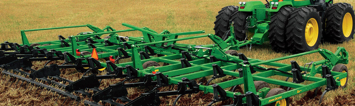 John Deere primary tillage machinery driving through a hay field